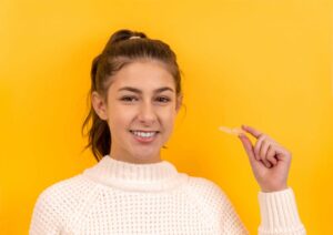 Young girl holding Invisalign clear aligners