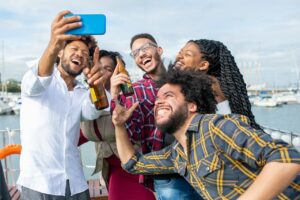 Group of friends smiling and taking a selfie together outdoors in summer